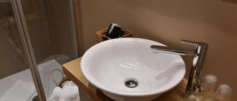 A bathroom with a white sink, chrome faucet, and a wooden vanity.