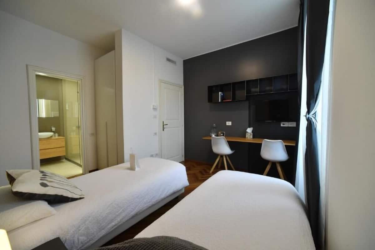 Hotelkamer met twee bedden, een bureau, een stoel, een spiegel en een kitchenette.