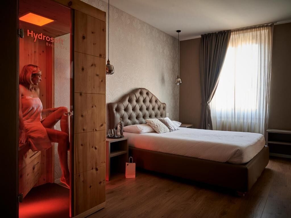 A bedroom with a large bed, wooden wardrobe, and a window with curtains.
