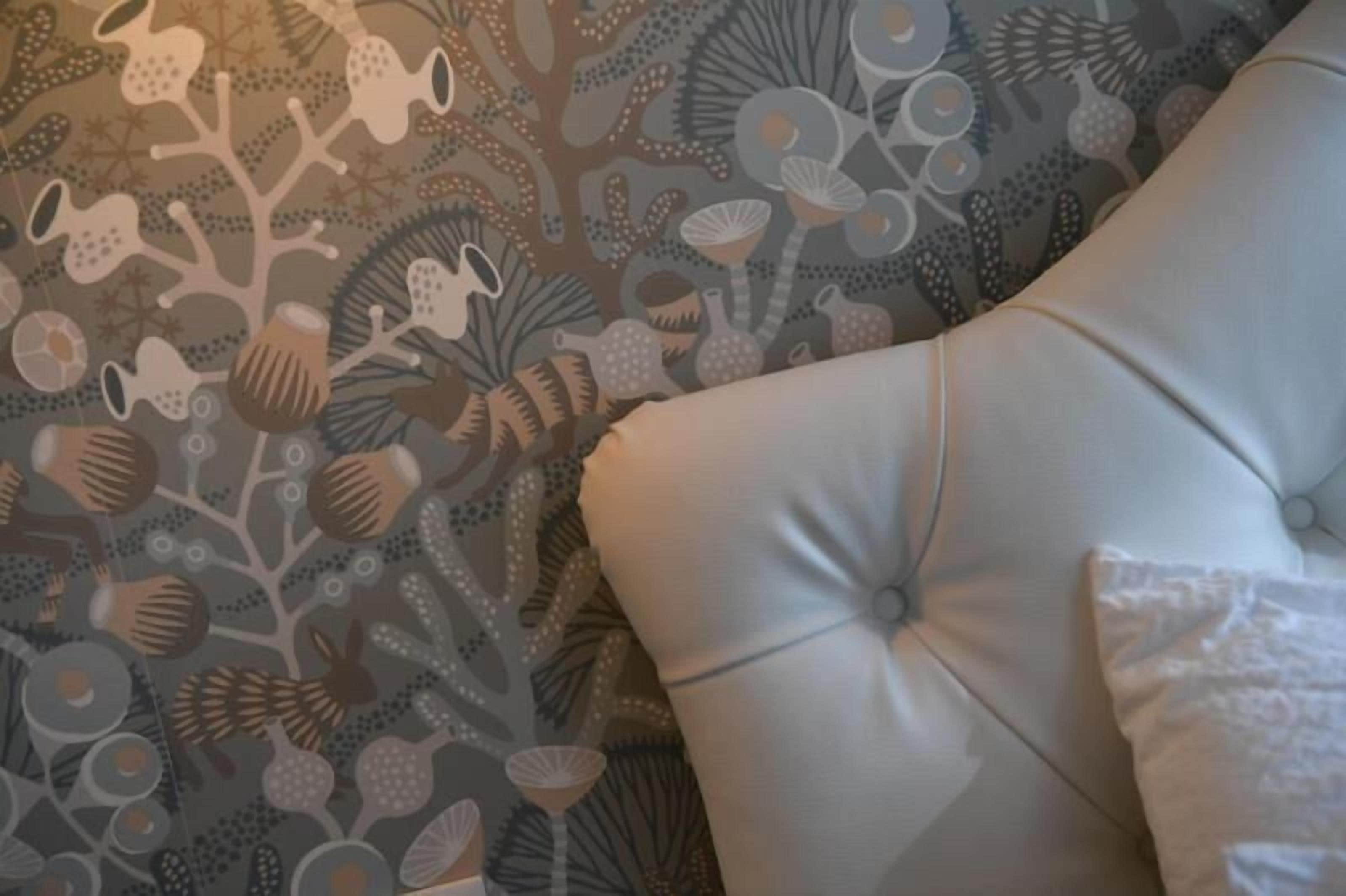 A tufted headboard with a patterned wallpaper featuring abstract shapes and designs.