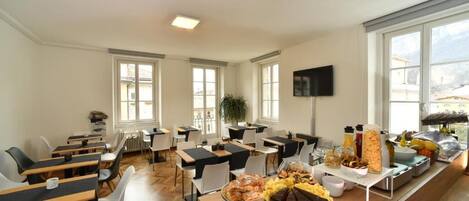 A dining area with tables, chairs, and a buffet with various food items.
