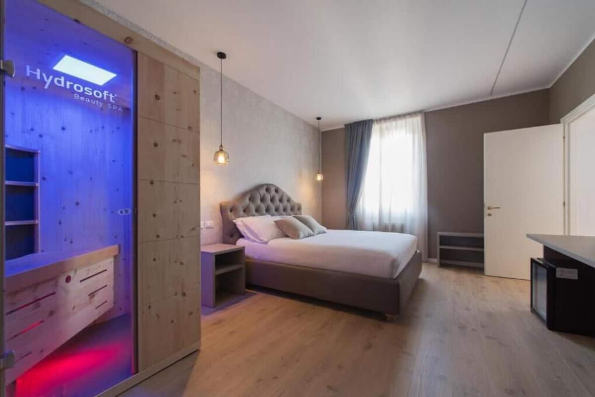 Een slaapkamer met een bed, nachtkastjes, een kledingkast en een Hydrosoft Beauty Spa bord.