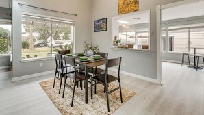 A dining area with a table set for four, a large window, and a view of parked cars outside. - Houston Family Retreat w/ Patio: Near Downtown! (Houston)