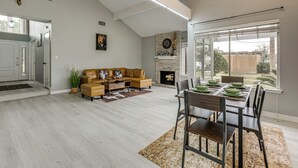 A spacious living room with a fireplace, a dining area with a table set for four, and a large window offering a view of the outdoors. - Houston Family Retreat w/ Patio: Near Downtown! (Houston)