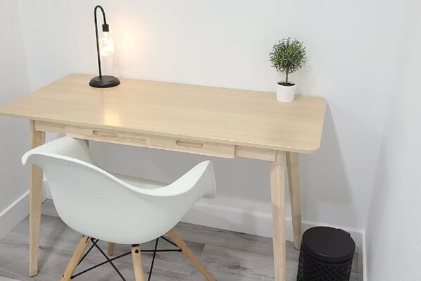 A wooden desk with a white chair, a small potted plant, and a trash bin. - Cozy Modern 2-Bd Guest House in Quiet neighborhood! (San Bernardino)