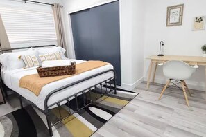 Un dormitori amb un llit, una taula de nit i un escriptori amb una cadira.