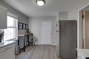 A kitchen with a stainless steel refrigerator, a window, a door, and a small bar stool. - 2 Mi to Downtown Minneapolis! Convenient Apt (Minneapolis)
