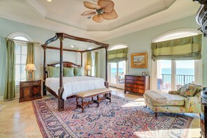 A spacious bedroom with a four-poster bed, a large ornate ceiling fan, a floral sofa, and a view of the ocean through the windows. - 'Like No Other' in the Panhandle of Florida (Seacrest Beach)