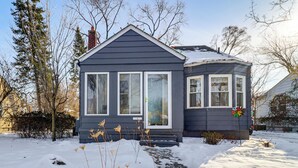 A two-story house with a dark gray exterior and white trim, featuring a front porch and a chimney. - Families Welcome! Colorful Berkley Home w/ Yard (Berkley)
