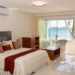 A hotel room with a bed, a desk, a chair, and a view of the sea. - Barracuda Eco Resort (Búzios)
