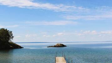 A pier extending into calm waters with a clear sky above.