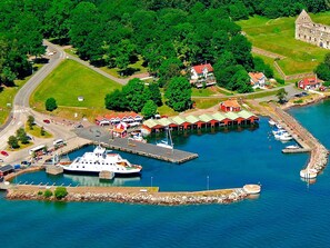 An aerial view of a marina with boats docked, a large white boat in the foreground, and several red-roofed buildings. - 4 Star Holiday Home in Odeshog (Odeshog)