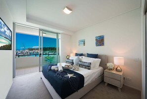 Ein Schlafzimmer mit Bett, Nachttischen und Blick auf eine Marina.
