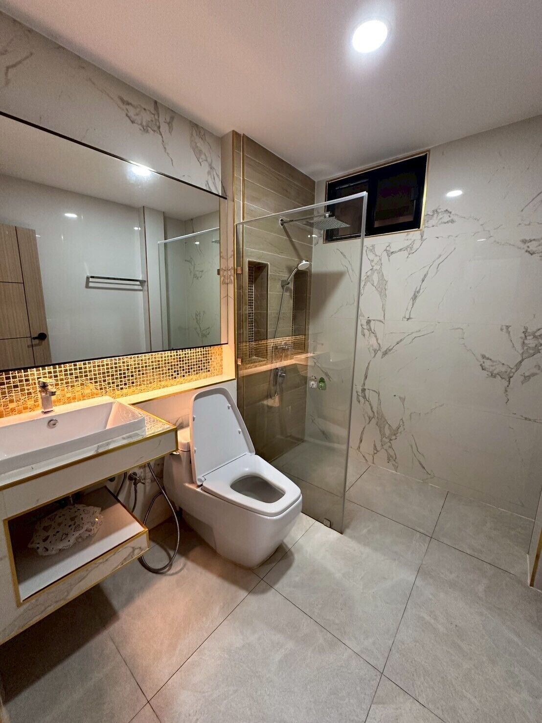 A modern bathroom with a glass-enclosed shower, a white toilet, and a vanity with a mirror.