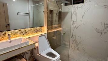 A modern bathroom with a glass-enclosed shower, a white toilet, and a vanity with a mirror.
