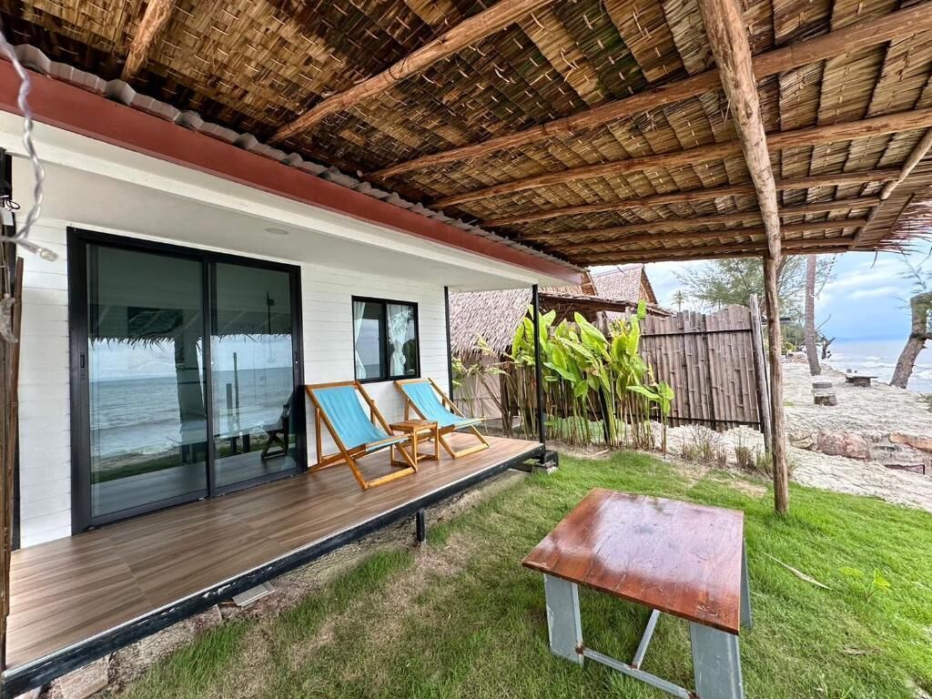 Ein modernes Haus mit einer Holterrasse, Glasschiebetüren und Blick auf den Strand.