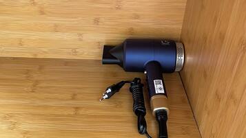 A black hairdryer with a cord and power adapter on a wooden surface.