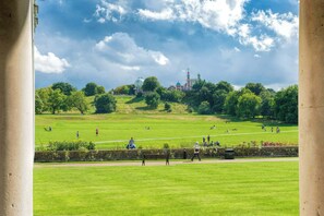 A park with a large open grassy area, a few benches, and a distant view of a building with domes and spires. - Bright 1BDR Flat near Greenwich Park n Blackheath (Greater London)