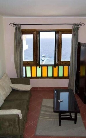 Een kamer met uitzicht op zee, een bank, een tafel en een televisie.