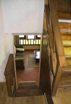 Una escalera de madera que conduce a una sala de estar con un sofá y una mesa.