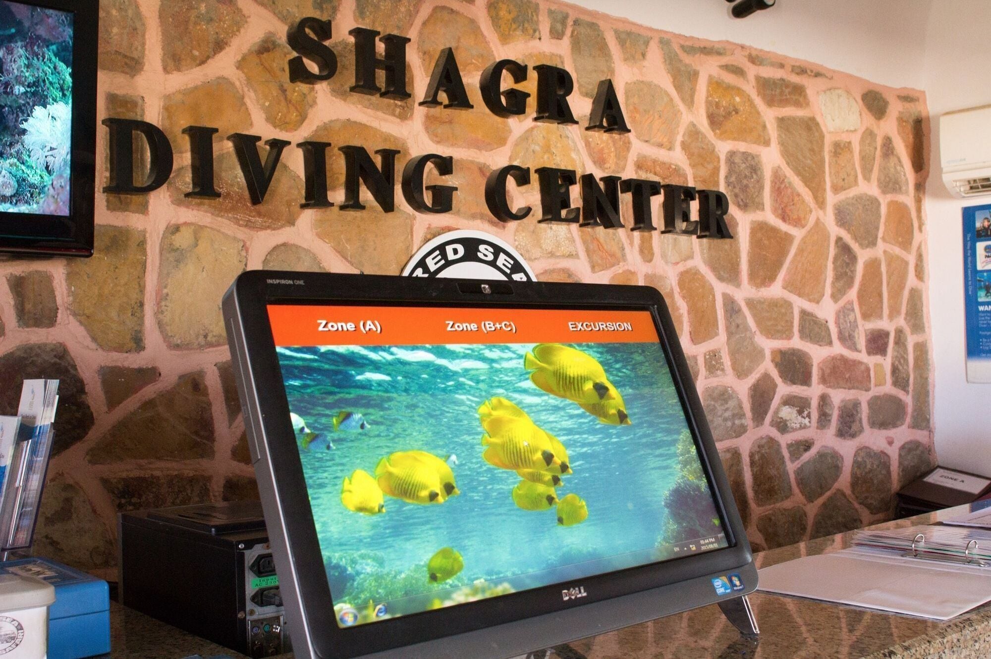 A computer monitor displaying a diving center sign and a screen with yellow fish.