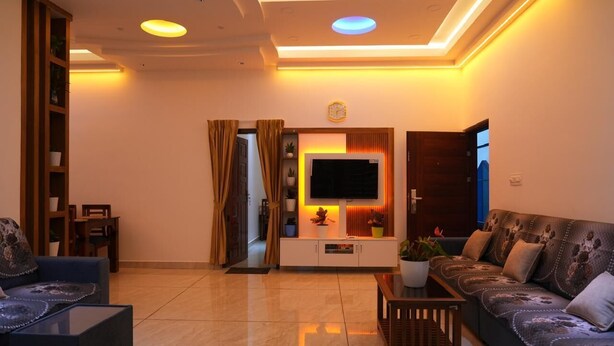Una sala de estar moderna con un televisor de pantalla plana, un sofá, una mesa de centro y una estantería.