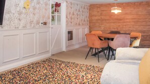 Een eethoek met een houten wand, witte lambrisering en een kleurrijk tapijt.