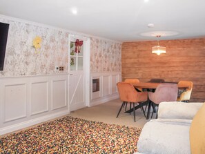 A dining area with a wooden wall, white paneling, and a colorful rug. - The Pump House - UK50648 (Falmouth)