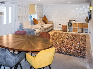 A cozy living room with a round wooden table, a sofa, and a colorful rug. - The Pump House - UK50648 (Falmouth)