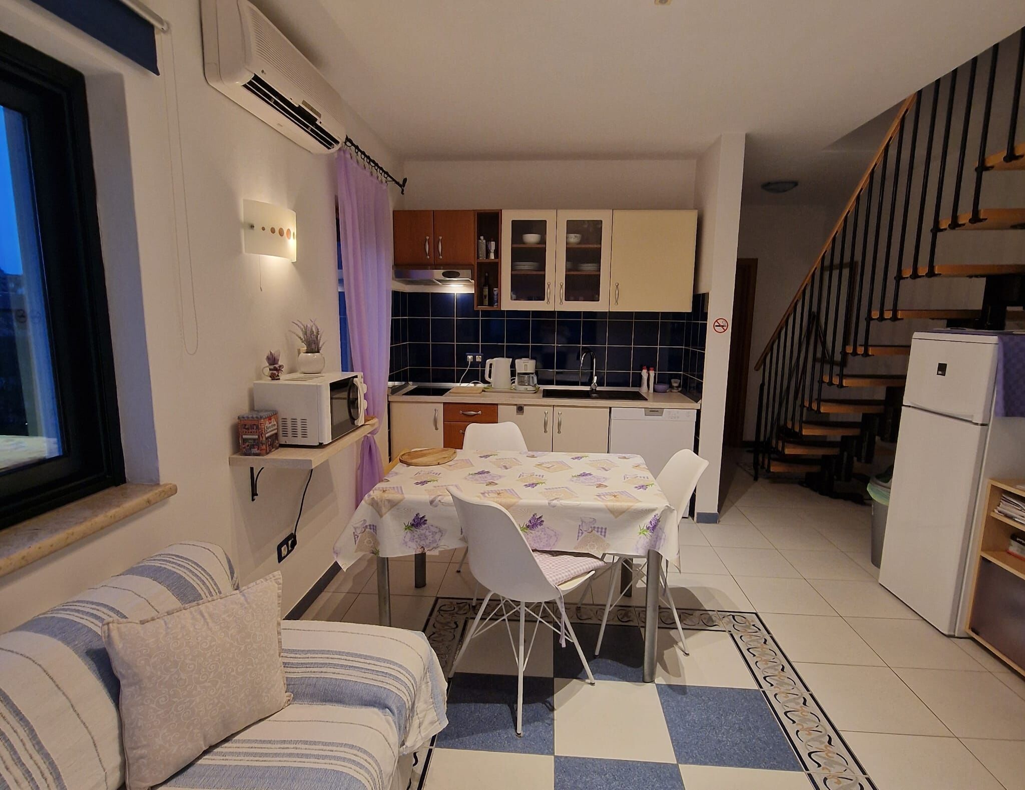 A compact kitchen with a dining table, chairs, a microwave, and a refrigerator.