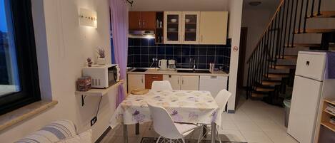 A compact kitchen with a dining table, chairs, a microwave, and a refrigerator.