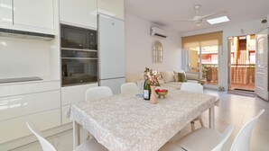 Eine moderne Küche mit integrierten Geräten, ein Essbereich mit Tisch und Stühlen sowie ein Blick auf den Balkon.