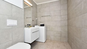 A modern bathroom with a toilet, sink, and mirror. - Oslo Apartments Observatoriegaten (Oslo)