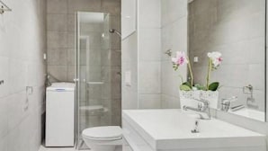 A modern bathroom with a glass shower enclosure, a toilet, and a vanity with a mirror. - Oslo Apartments Observatoriegaten (Oslo)