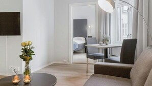 A modern living room with a sofa, a coffee table with candles, a vase with flowers, and a view into a bedroom through an open door. - Oslo Apartments Observatoriegaten (Oslo)