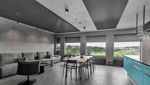 A modern kitchen with a dining area, large windows, and a view of the outdoors. - Hotel Gardur (Reykjavik)