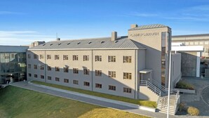 A modern building with a flat roof, multiple windows, and a staircase leading to an upper level. - Hotel Gardur (Reykjavik)