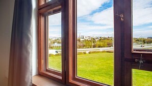 A window with a view of a green landscape and a road. - Hotel Gardur (Reykjavik)
