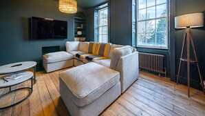 A modern living room with a sectional sofa, a round coffee table, and a floor lamp. - Stunning Luxury Holiday Home in Bath (Bath)
