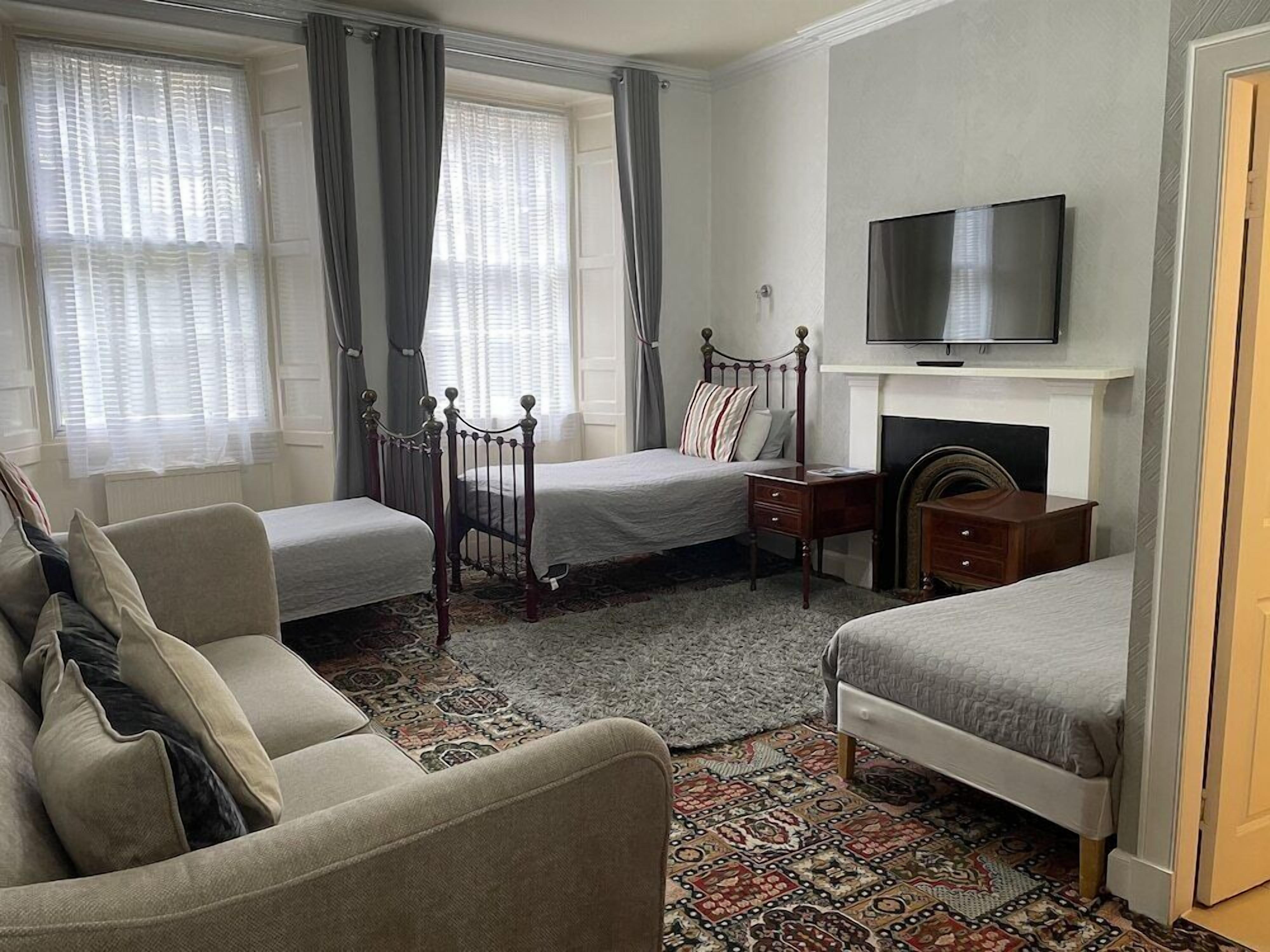 Una habitación de hotel con dos camas individuales, un sofá, un televisor y una chimenea.