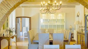 Un espace repas agrémenté d’un lustre, d’une grande fenêtre à vitres dépolies et d’une arche en briques.