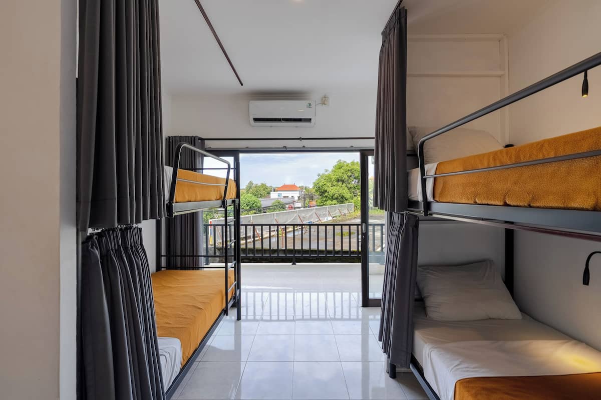 Une chambre de dortoir avec des lits superposés, un balcon et un appareil de climatisation.