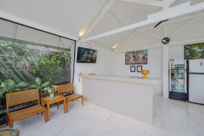 Un interior moderno con un mostrador de recepción, una zona de estar y un refrigerador.