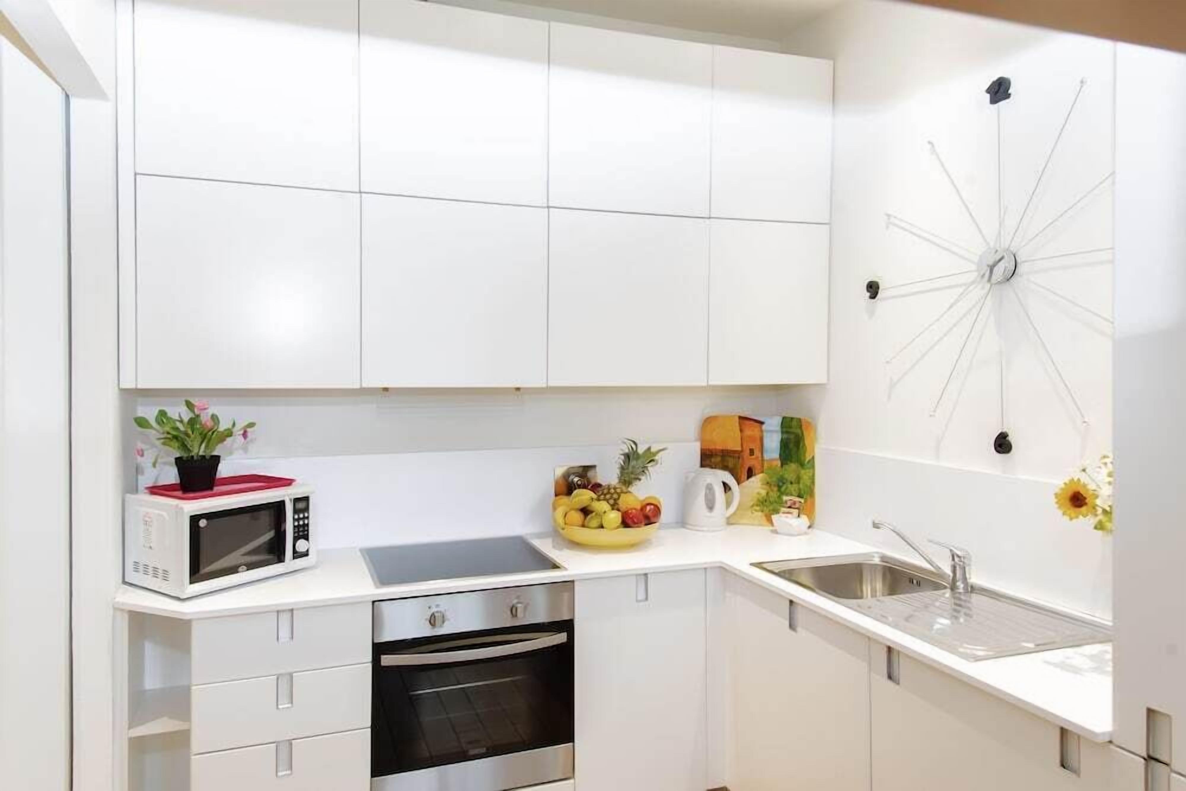 Una cocina moderna con armarios blancos, un microondas, una estufa y un lavaplatos.