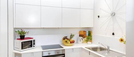 Una cocina moderna con armarios blancos, un microondas, una estufa y un lavaplatos.