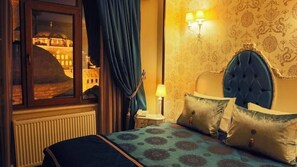 Et hotelværelse med en seng, et natbord, en lampe, et vindue med udsigt til en bygning og tapet med mønster.