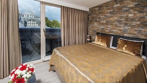 Une chambre d’hôtel avec un grand lit, un mur en pierre et une vue sur un immeuble par la fenêtre.