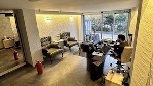 Une chambre d’hôtel moderne dotée d’un grand bureau, de deux canapés confortables, d’une petite table et offrant une vue sur l’extérieur.