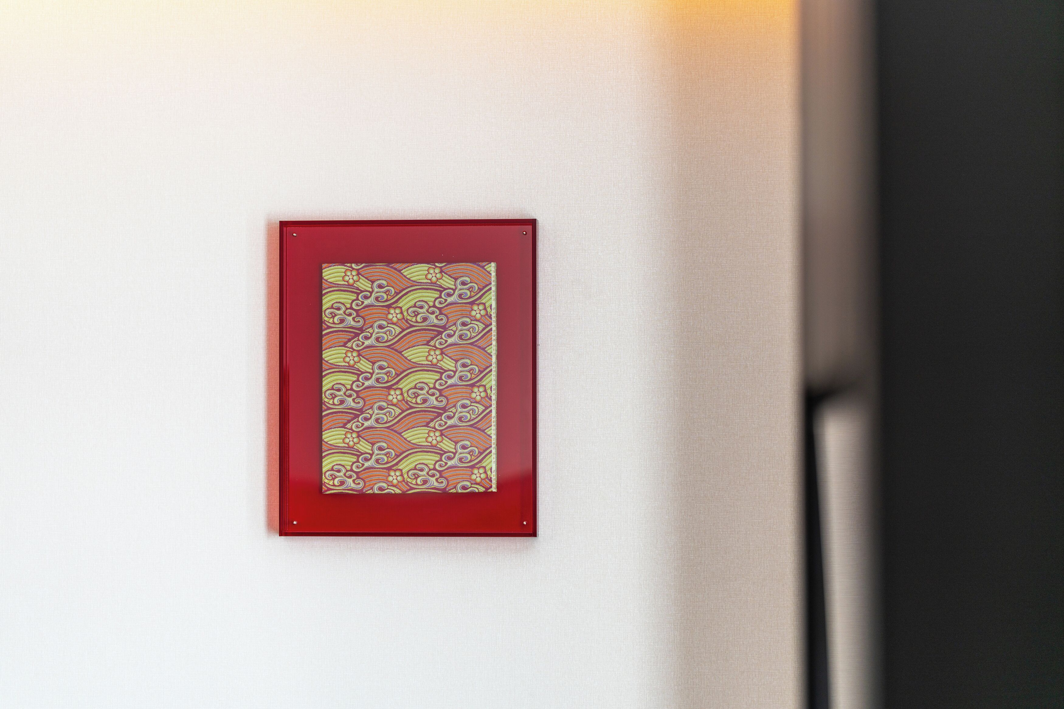 A framed artwork with a traditional pattern on a wall.