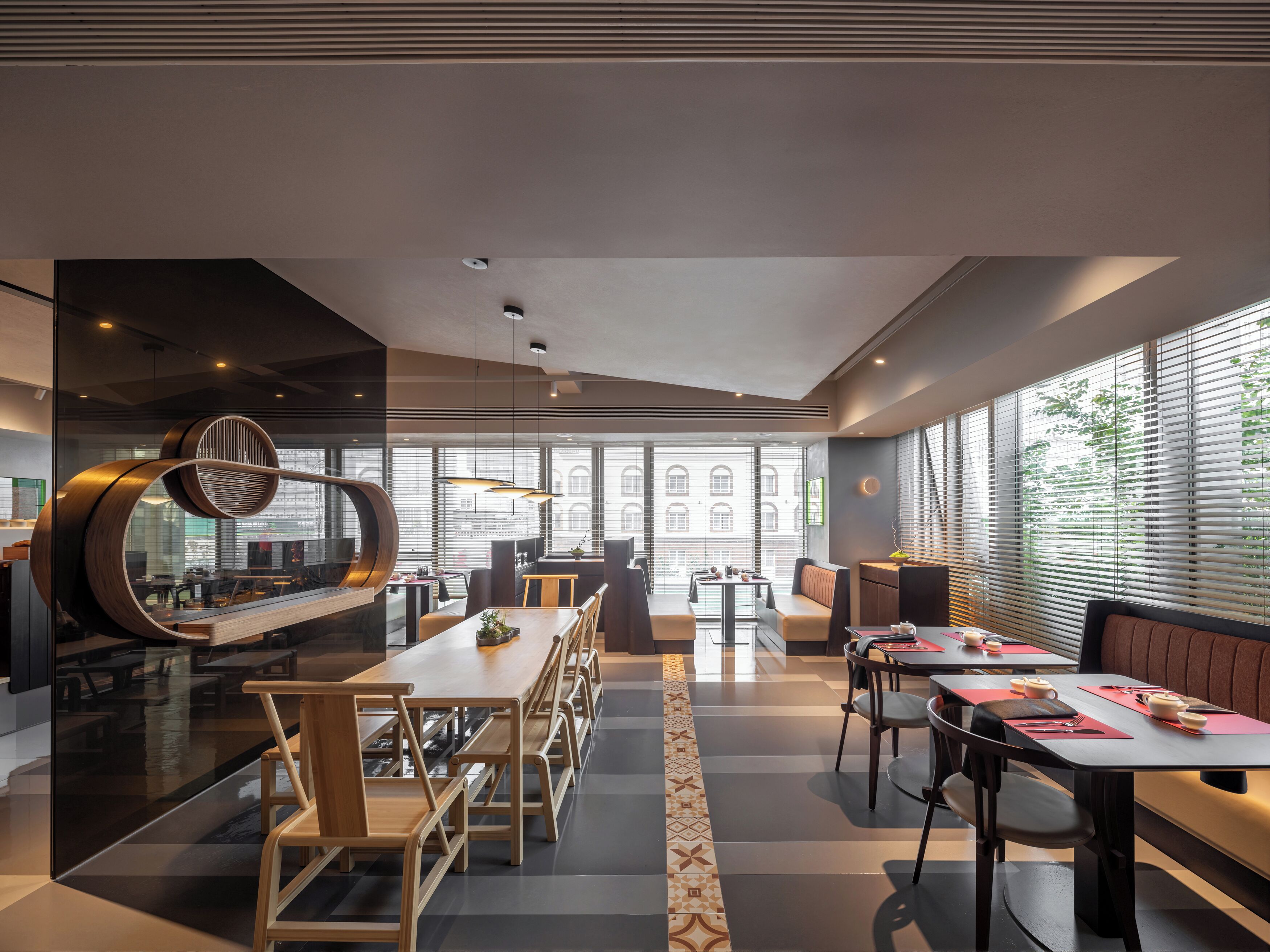 Een modern restaurant met een lange gedeelde tafel, afzonderlijke zitjes en een bar.